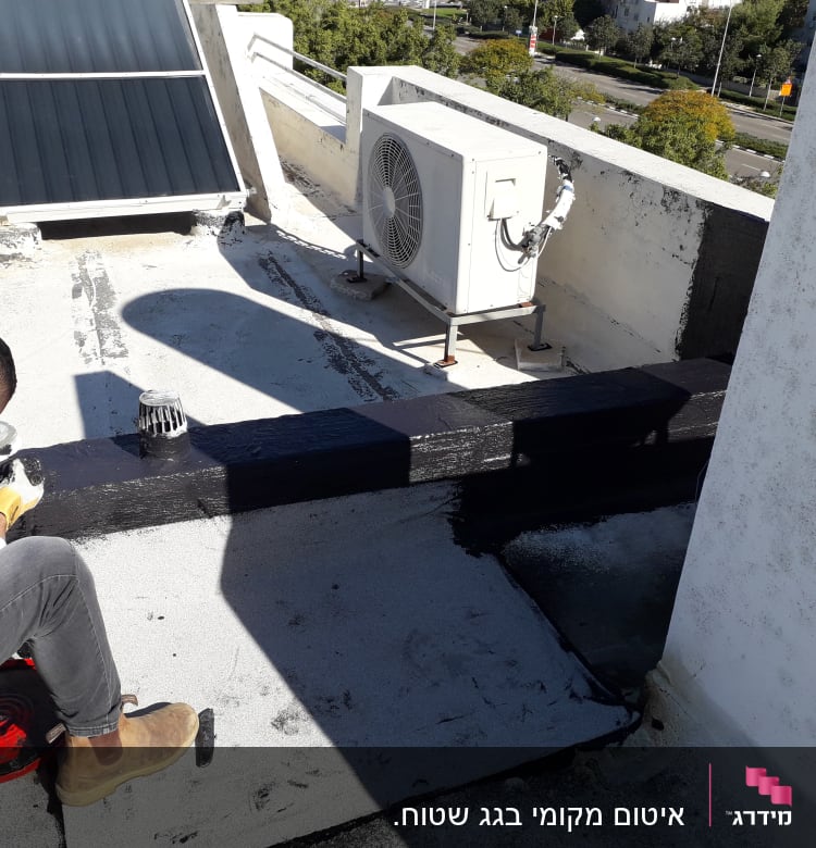 אדם מורח חומר איטום על גג שטוח